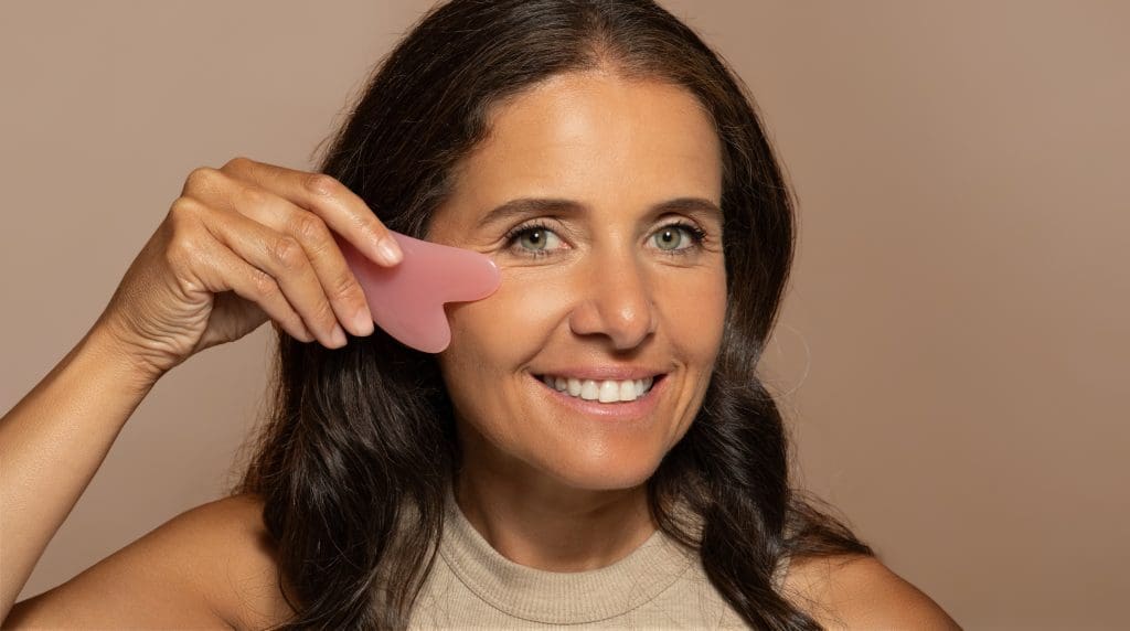 a middle aged woman doing a facial massage for gua sha wrinkles