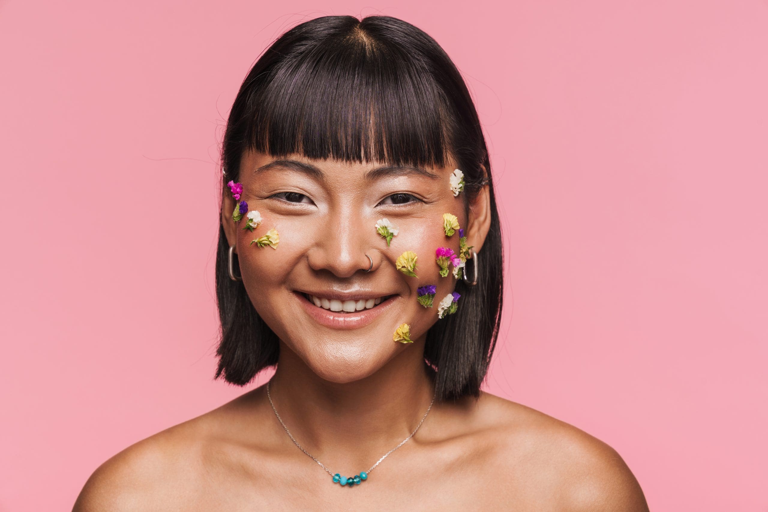 a young asian woman with makeup facial decoration against a pink background symbolizing ozone sauna therapy clear skin