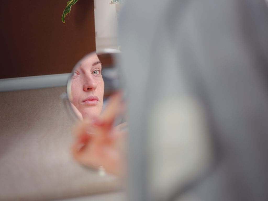 a woman looking into the mirror wondering if endospheres therapy can help her lose stubborn fat