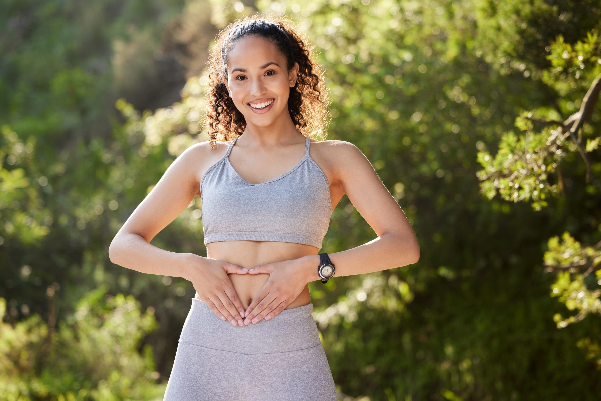 a woman forming a heart shape with her hands on her stomach to celebrate National Women's Health and Fitness Day