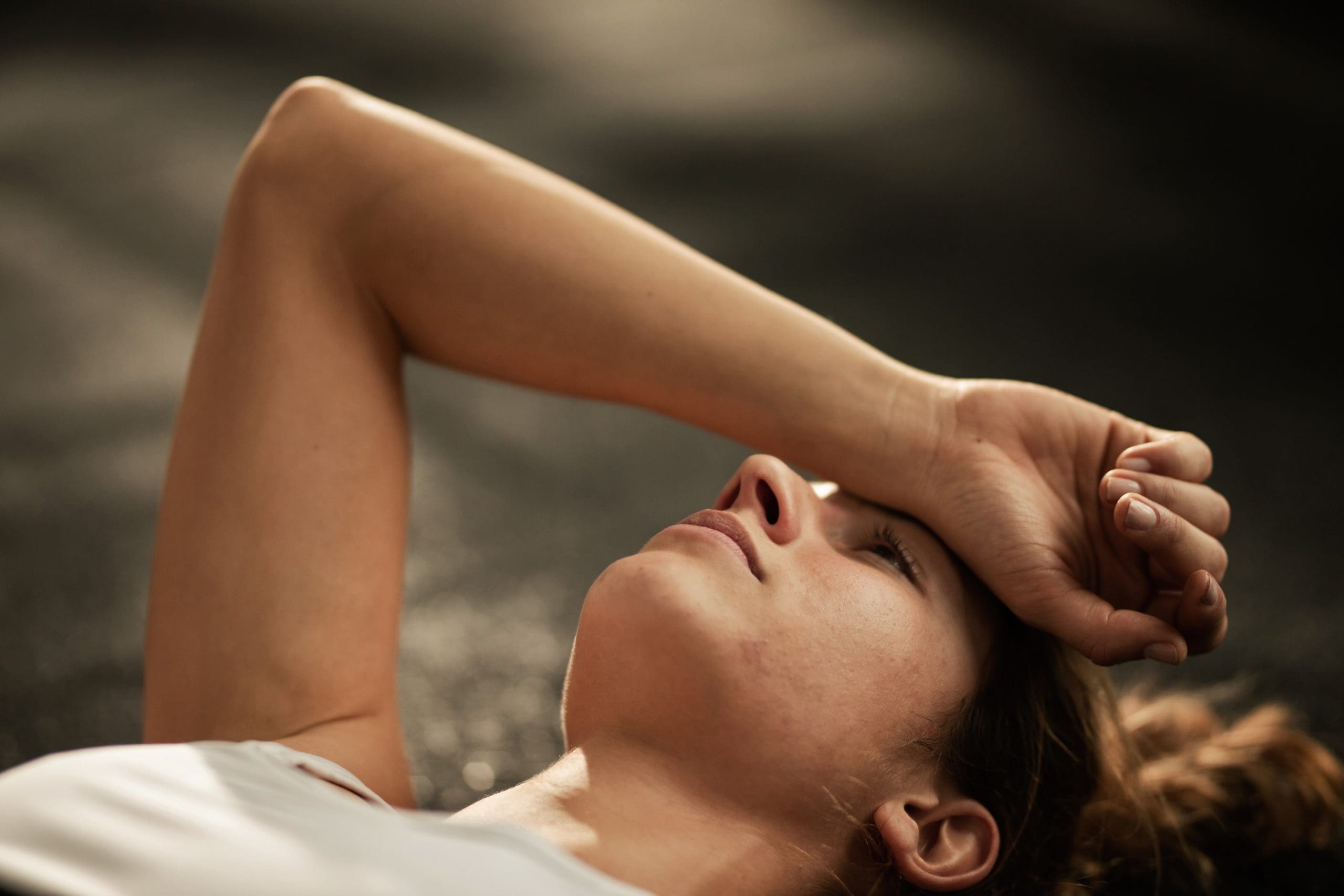a woman laying down with her arm across her face to show that ozone sauna therapy can provide relief for Fibromyalgia symptoms
