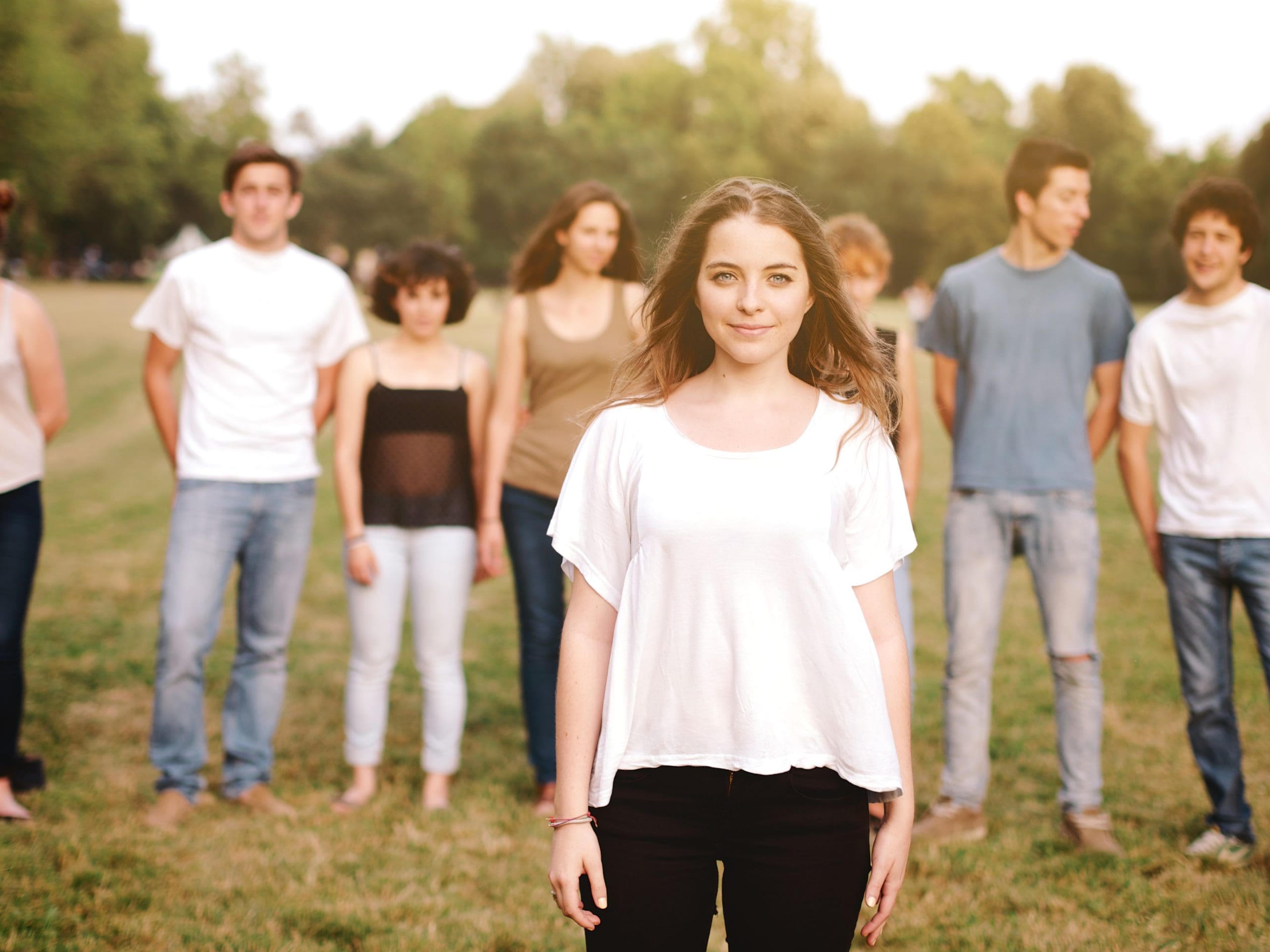 a girl in the forground looking at us with her friends in the background to show the importance of National Health Education Week