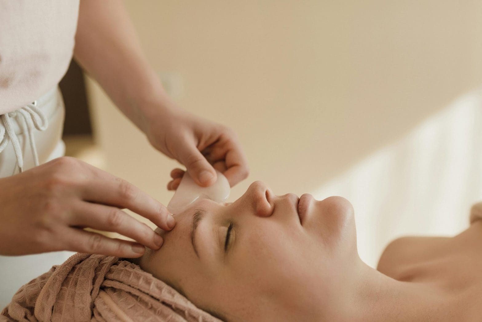 a woman getting a gua sha facial as opposed to a traditional facial