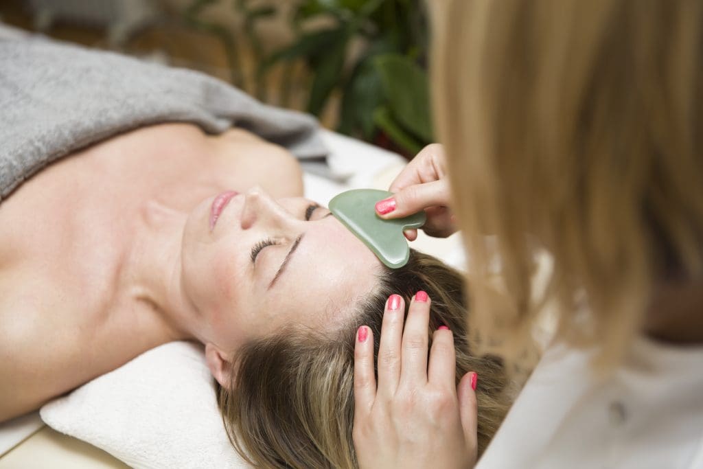 a woman getting gua sha facial mapping