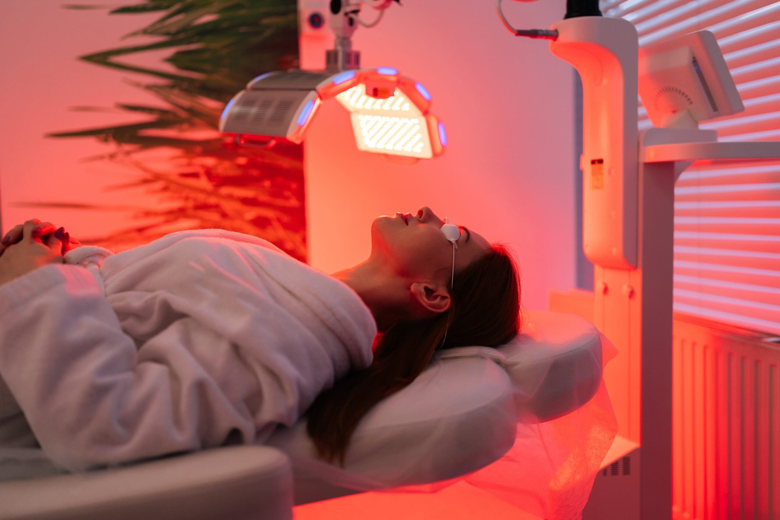 red light therapy panel glowing on a client’s face during skin rejuvenation treatment