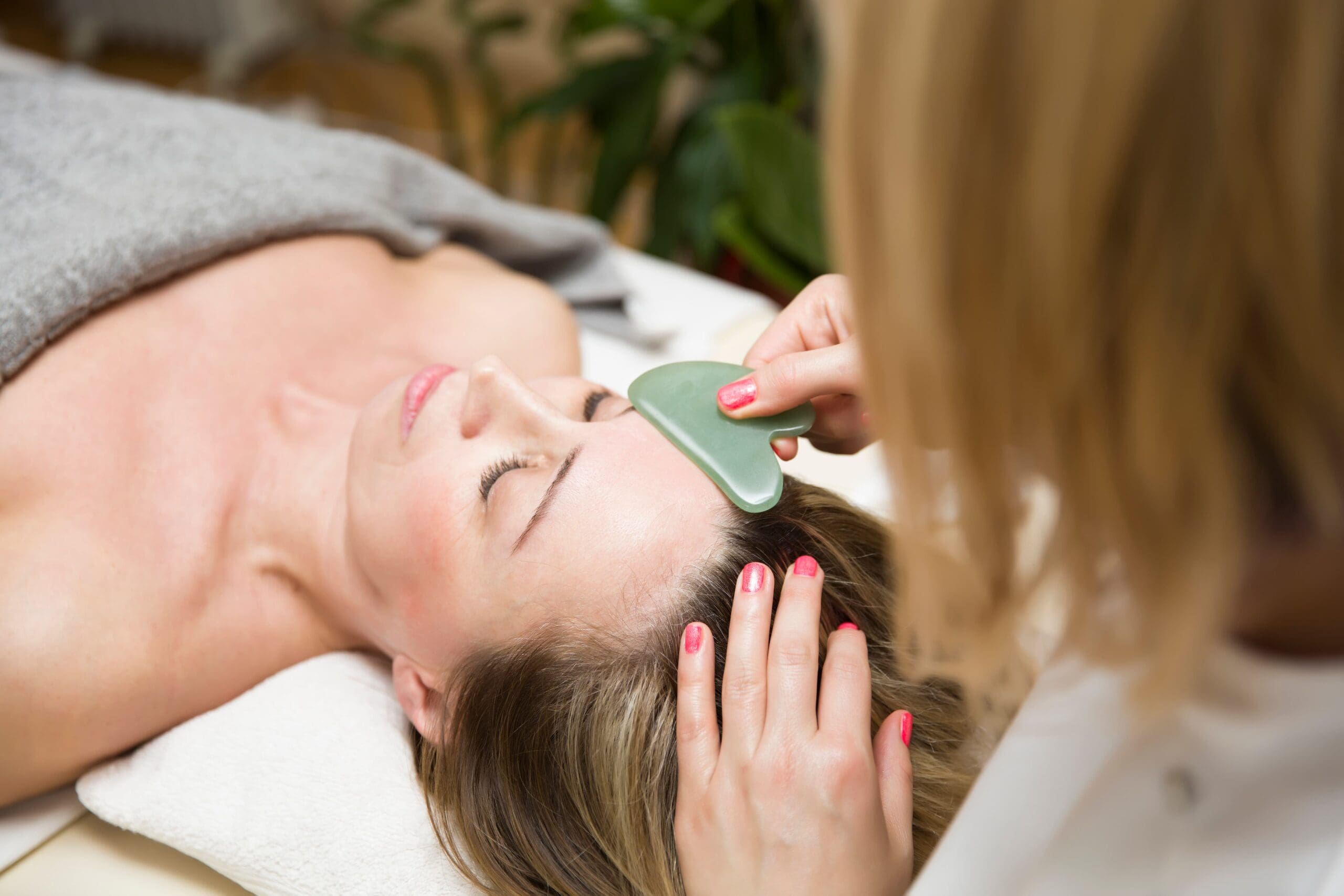 Woman receiving gua sha therapy at a serene wellness spa