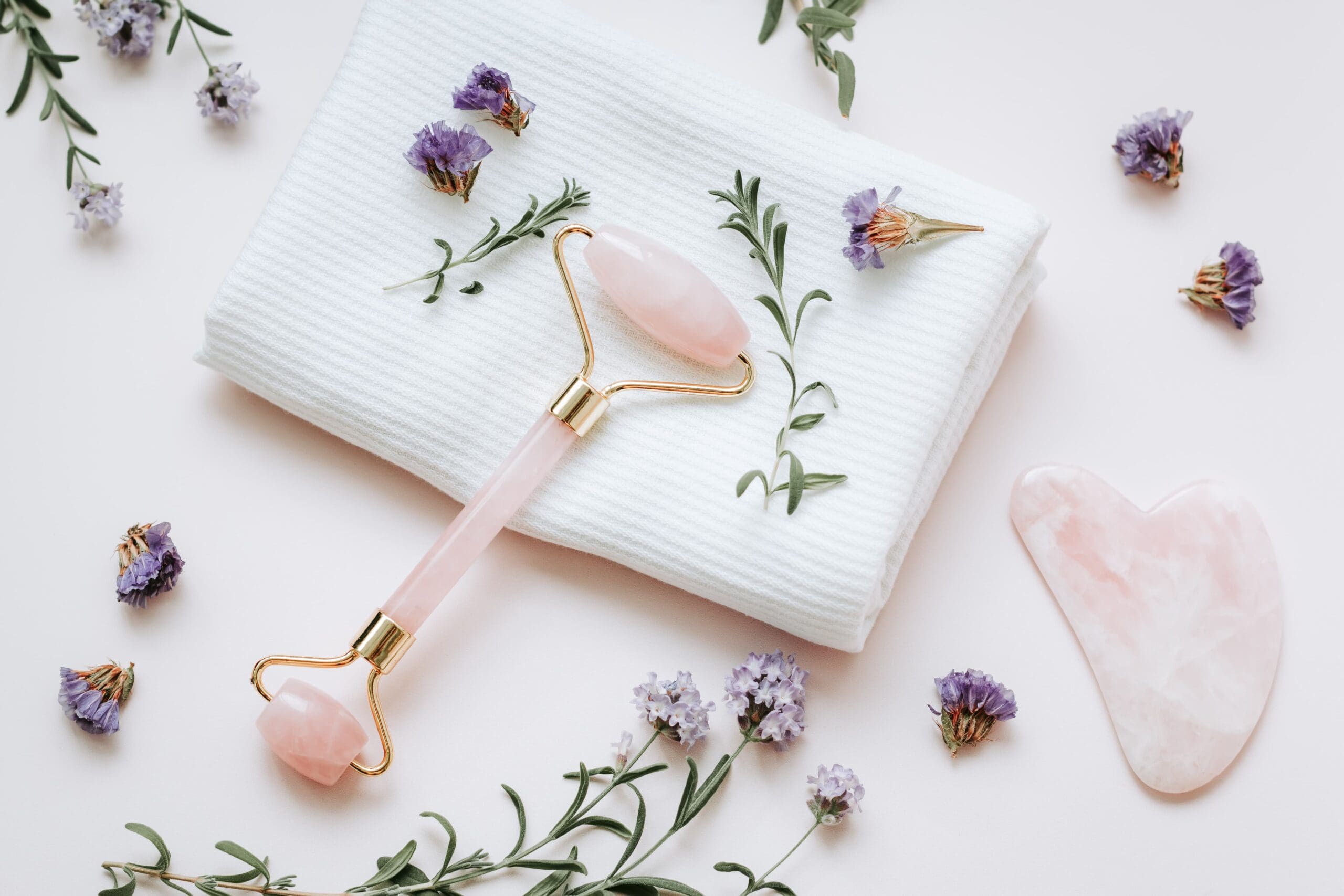 Jade and rose quartz gua sha tools next to natural oils