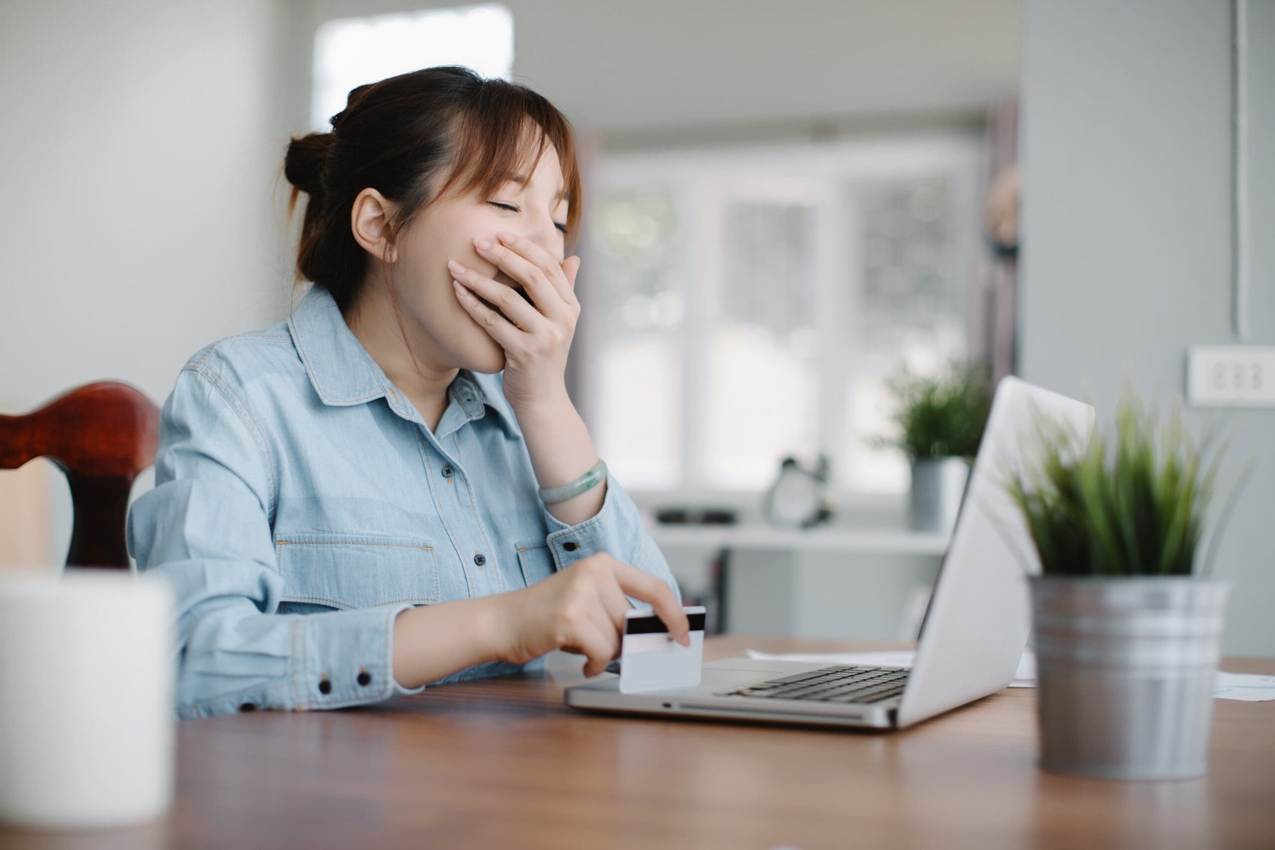 Person sitting at a desk yawning, coffee cup beside them