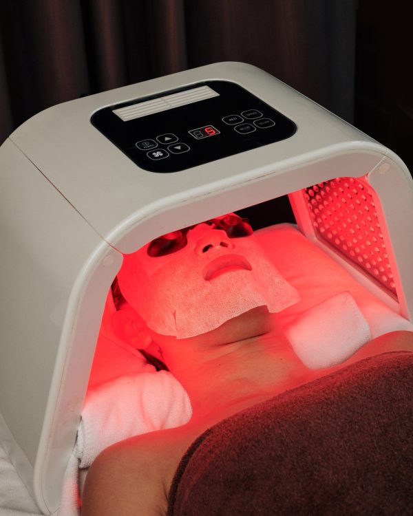 a woman under a red light therapy machine at Empower Wellness Spa